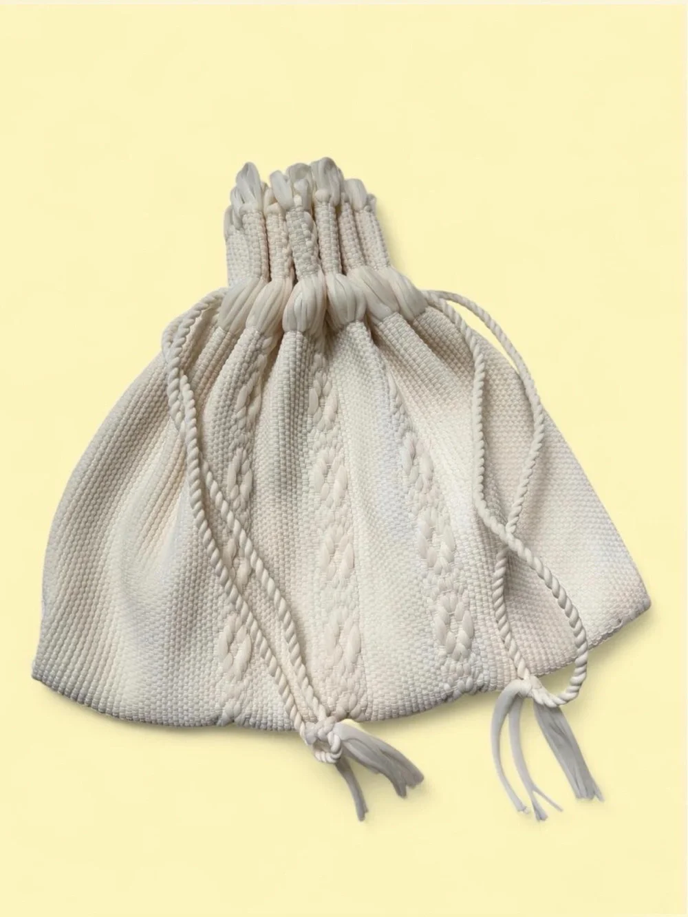 Cream cable knit drawstring bag with braided rope details